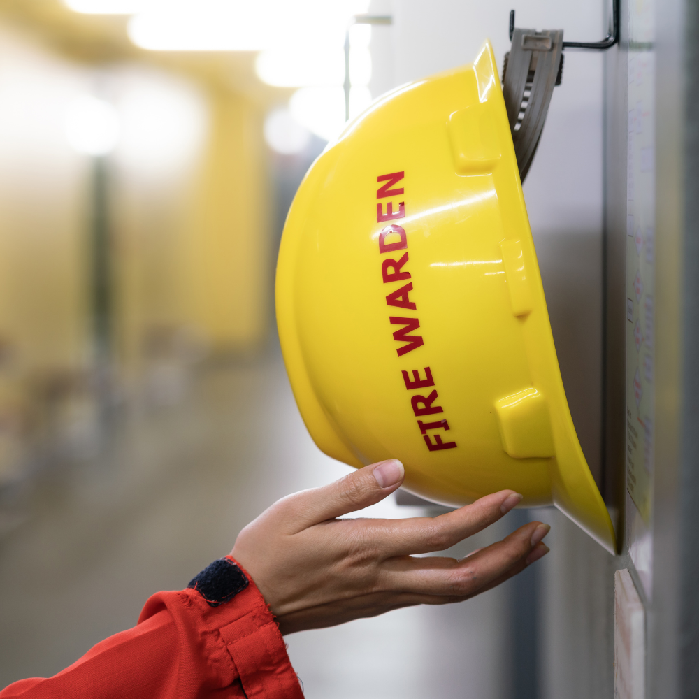Fire Warden reaches for fire safety hat during a Fire Warden Training course held in Australia and taught by Fire Safe Australia and New Zealand. This image features a yellow fire warden cap, with red writting.